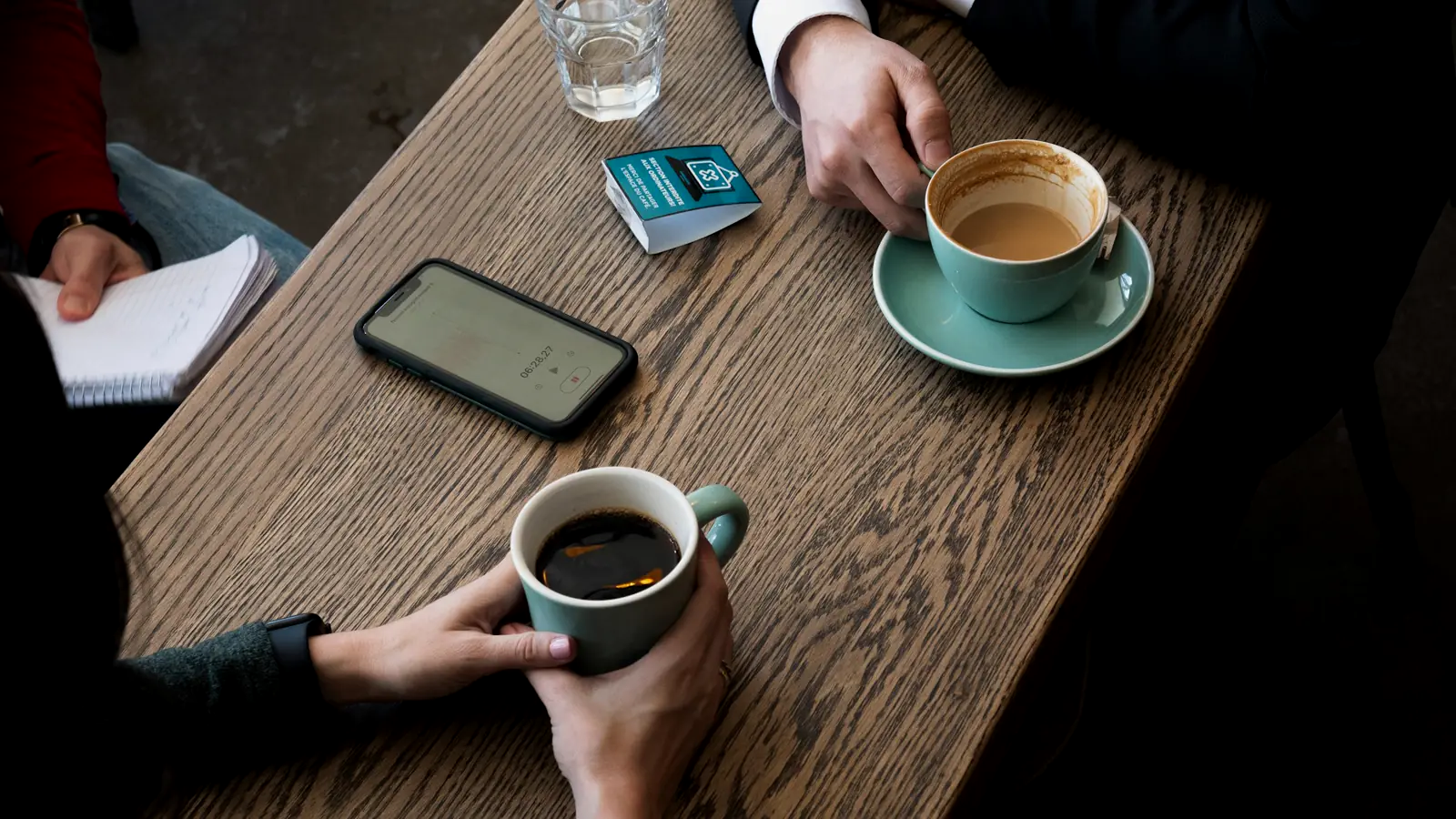 Zwei Menschen sitzen bei Kaffee an einem Tisch und sprechen miteinander